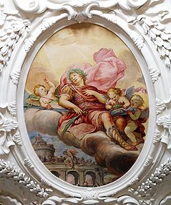 Glorie des Hl. Quirin auf einem Fresko in der Pfarrkirche Tegernsee-St. Quirinus, gestaltet 1693 von Hans Georg Asam (1649-1711). Im Vordergrund befindet sich Quirinus mit den Zeichen des Märtyriums, Schwert und Palmzweig. Im Hintergrund ist zu sehen, wie der Körper des enthaupteten Märtyrers in den Tiber gestoßen wird, weil er seinem christlichen Glauben nicht abschwörte. Die sterblichen Überreste des Heiligen gelangten im späten 8. Jahrhundert nach Tegernsee. (Foto: Daniel Rittenauer)