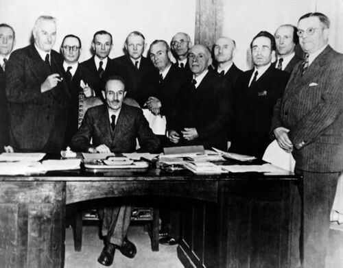 Gruppenaufnahme des Kabinetts Hoegner I. Von links nach rechts: Hans Meinzolt (1887-1967), Albert Rosshaupter (1878-1949), Anton Pfeiffer (1888-1957), Hans Ehard (1887-1980), Ludwig Erhard (1897-1977), Josef Seifried (1892-1962), Franz Fendt (1892-1982), Fritz Terhalle (1889-1962), Heinrich Krehle (1892-1969), Josef Baumgartner, Ludwig Ficker (1904-1947), Hans Müller (1884-1961). Sitzend: Wilhelm Hoegner. (Bildarchiv Bayerischer Landtag, Bildnr. AA02615A)