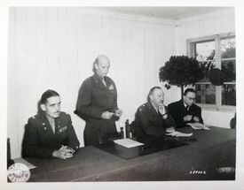 Rede von Generalmajor Horace L. McBride am 10. Oktober 1946 zur Übertragung der Internierungslager an die bayerischen Behörden. Anwesend von links: Colonel Charles Pennoyer Bixel, General McBride, Brigadegeneral Walter J. Muller, Anton Pfeiffer. (National Archives Washington, SC 259002 / Stadtarchiv Moosburg)