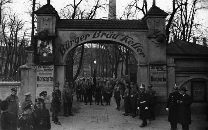 Bürgerbräukeller, Rosenheimer Straße 29, Gedenkfeier am 8./9. November 1933; Marschkolonne mit "Blutfahne", SS-Angehörige und Polizisten. (Bayerische Staatsbibliothek, Bildarchiv hoff-8542)