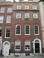 Der pfalzbayerische Gesandte Joseph Graf von Haslang (1699-1783) wohnte in seinen späten Jahren in einem Haus am Londoner Golden Square 24, das zuvor der portugische Botschafter bewohnt hatte. Die dahinterliegende katholische Gesandtschaftskapelle wurde 1780 während eines Aufstandes beschädigt und erneuert. (Foto von Joachim Specht lizensiert durch CC-BY-SA 4.0 via Wikimedia Commons)