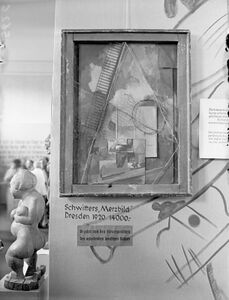 Ausschnitt aus der Dada-Wand mit dem Gemälde "Merzbild" von Kurt Schwitters (1887-1948) und dem Etikett "Bezahlt von den Steuergroschen des arbeitenden deutschen Volkes". Foto: Kurt Huhle. (Stadtarchiv München, DE-1992-FS-NS-01573)