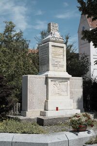 Beispiel für ein um die Opfer des Zweiten Weltkrieges ergänztes Denkmal in Unterpfaffenhofen. Die Gefallenen des Ersten Weltkrieges sind auf den Seiten des 1921 errichteten Postaments aufgeführt. Nach 1945 wurden die Gefallenen des Zweiten Weltkriegs auf zwei angefügten Seitentafeln ergänzt. (Fotografie von Gfreihalter, lizenziert durch CC-BY-SA 3.0 via Wikimedia Commons)