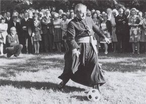 Bei einem Empfang der Katholischen und Evangelischen Kirche im Park der Akademie zielt Julius Kardinal Döpfner (1913-1976, seit 1961 Erzbischof von München und Freising) am 5. Juli 1974 zur Freude der Zuschauer auf eine Torwand anlässlich der Fußball-Weltmeisterschaft. (Foto: Katholische Akademie in Bayern)