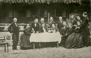 Tee-Gesellschaft vor dem Schweizer Haus in der Bleckenau am 24. August 1864, Vorabend des 19. Geburtstags Ludwigs II. Hinter dem König stehend Leibarzt Dr. Franz Xaver von Gietl (1803-1888), ganz rechts Adjutant Paul von Thurn und Taxis (1843-1879). Fotografie Joseph Albert (1825-1886). (Gemeinfrei via Wikimedia Commons)