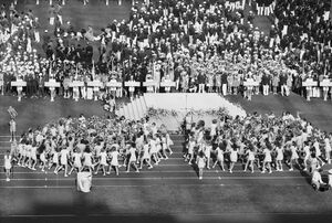 Die Eröffnungsfeier der XX. Olympischen Sommerspiele in München fand am Nachmittag des 26. August 1972 statt. Auf dem Bild ist der traditionelle Gruß der Jugend, dargeboten von 3500 Münchner Schulkindern mit selbst gebundenen Bögen und Blumensträußen, zu sehen. Foto von Karsten de Riese (geb. 1942). (Bayerische Staatsbibliothek, Bildarchiv rie-000029)